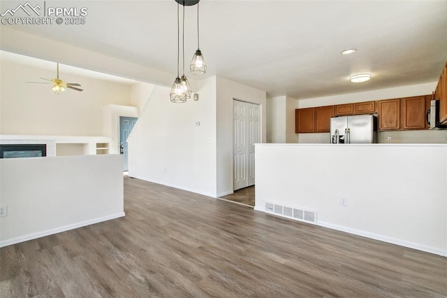 interior space with brown cabinets, visible vents, hanging light fixtures, appliances with stainless steel finishes, and open floor plan