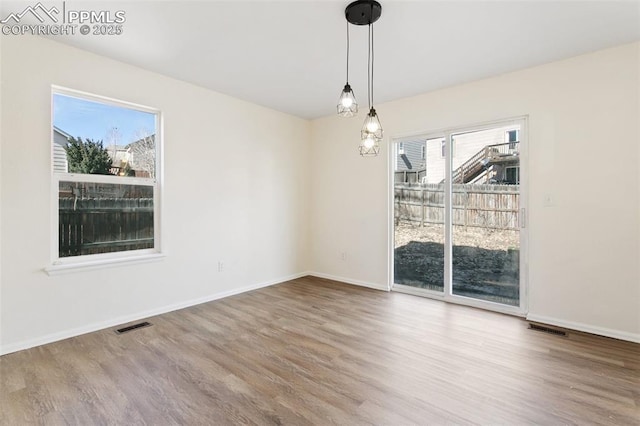 unfurnished dining area featuring wood finished floors, visible vents, and baseboards