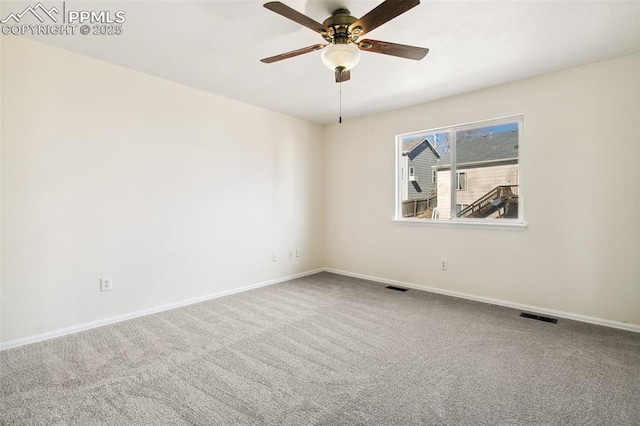 carpeted spare room with a ceiling fan, visible vents, and baseboards