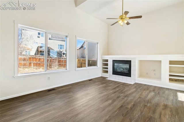 unfurnished living room featuring a wealth of natural light, dark wood-style flooring, visible vents, and a fireplace