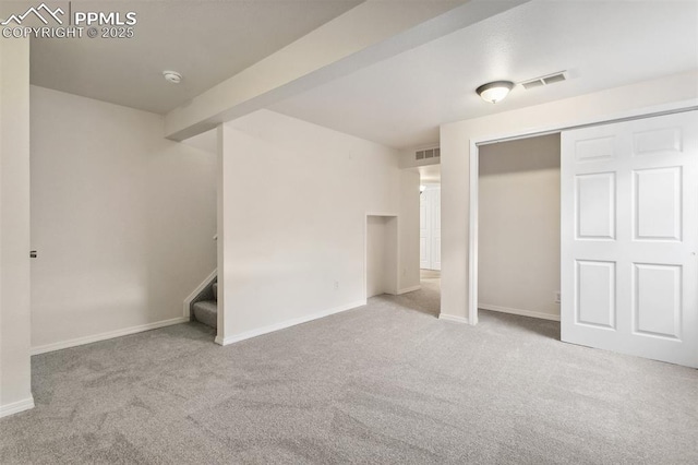 unfurnished bedroom featuring baseboards, beam ceiling, visible vents, and light colored carpet