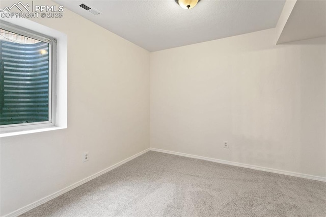 carpeted spare room with visible vents and baseboards