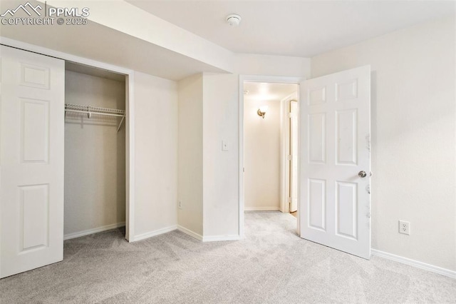 unfurnished bedroom featuring a closet, light carpet, and baseboards