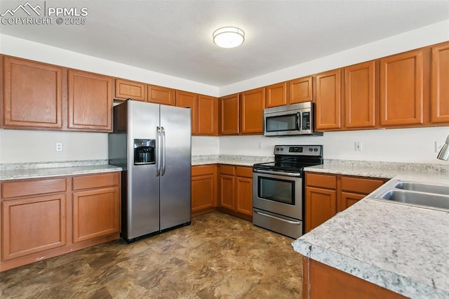 kitchen featuring stainless steel appliances, brown cabinets, light countertops, and a sink