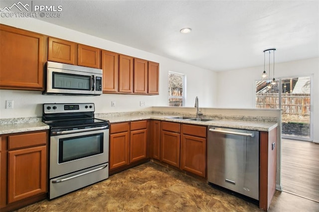 kitchen featuring a peninsula, a sink, light countertops, appliances with stainless steel finishes, and decorative light fixtures