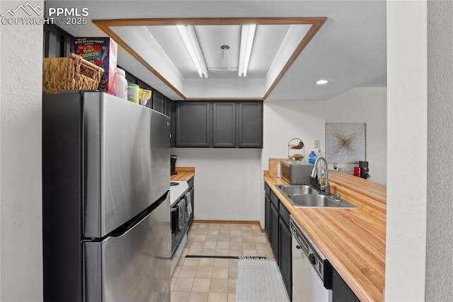 kitchen featuring white appliances, dark cabinetry, a sink, and wooden counters