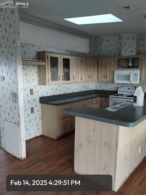 kitchen with dark countertops, white appliances, glass insert cabinets, and wallpapered walls