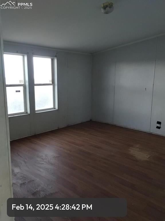 empty room with dark wood finished floors and crown molding