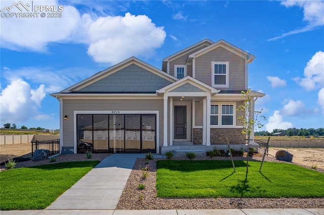 craftsman-style home with stone siding, a front lawn, and fence