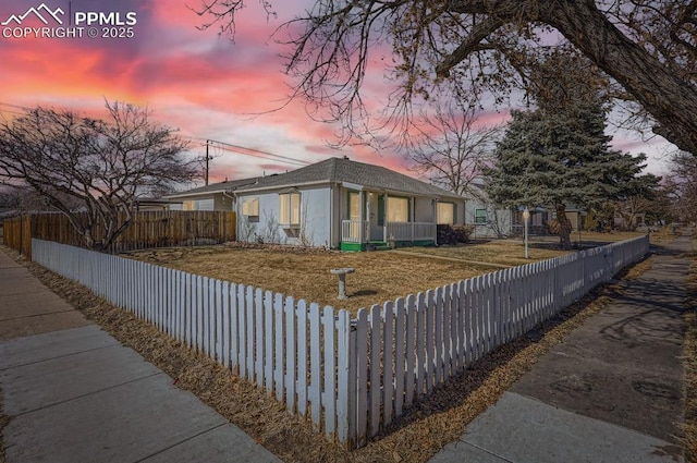 property exterior at dusk with a fenced front yard and stucco siding