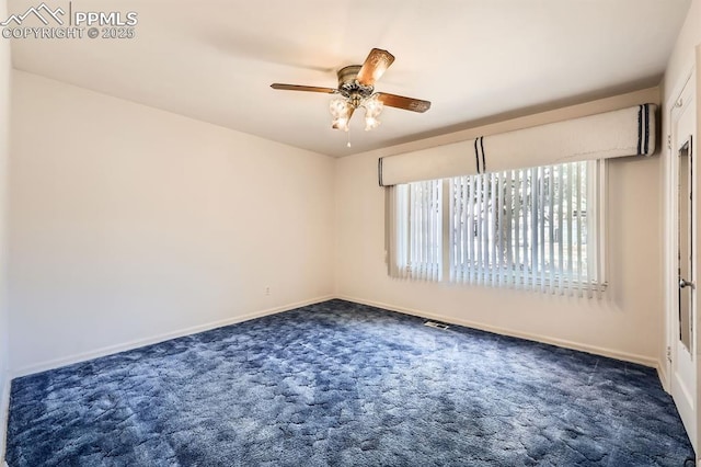 spare room with a ceiling fan, visible vents, dark carpet, and baseboards