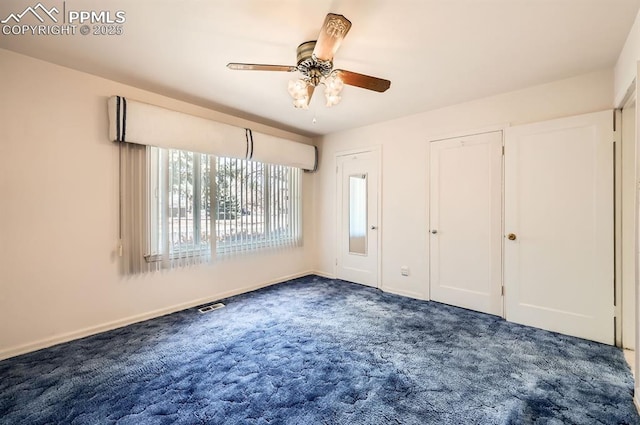 unfurnished bedroom featuring ceiling fan, dark carpet, visible vents, and baseboards