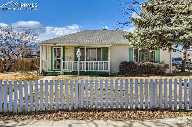 ranch-style home featuring a porch, a fenced front yard, a shingled roof, and stucco siding