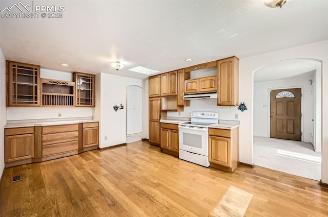 kitchen featuring white range with electric stovetop, arched walkways, light wood finished floors, open shelves, and under cabinet range hood