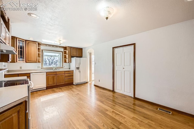 kitchen with white appliances, visible vents, arched walkways, light wood-style floors, and open shelves