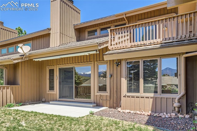 back of house featuring a balcony, a patio area, and board and batten siding