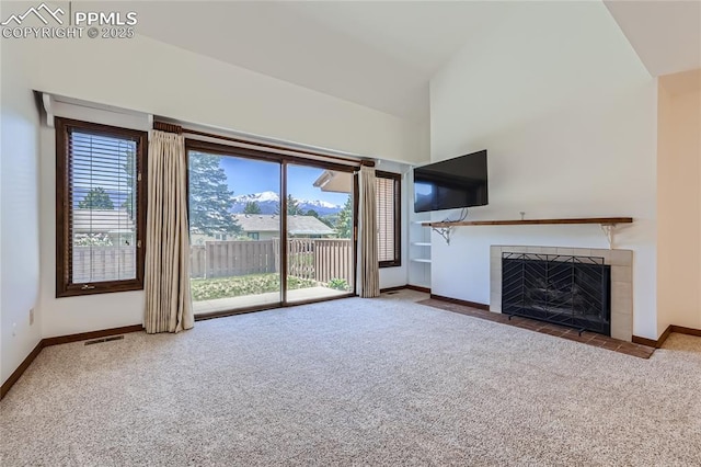 unfurnished living room featuring carpet floors, a fireplace, visible vents, and a wealth of natural light