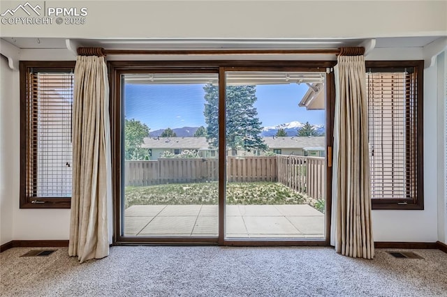 doorway to outside featuring carpet, a healthy amount of sunlight, and visible vents