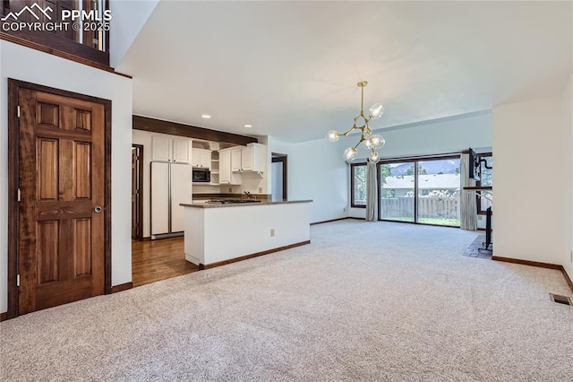 unfurnished living room featuring a chandelier, recessed lighting, light carpet, and baseboards