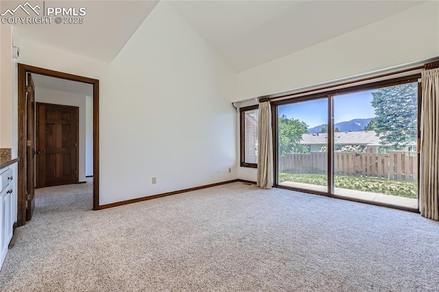 unfurnished room with light carpet, high vaulted ceiling, a mountain view, and baseboards