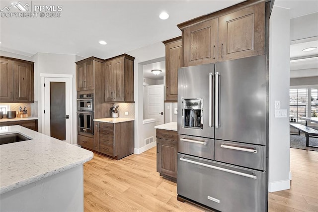 kitchen featuring tasteful backsplash, visible vents, stainless steel appliances, light wood-type flooring, and recessed lighting