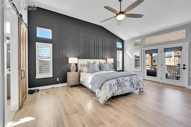 bedroom featuring lofted ceiling, ceiling fan, a barn door, wood finished floors, and access to outside