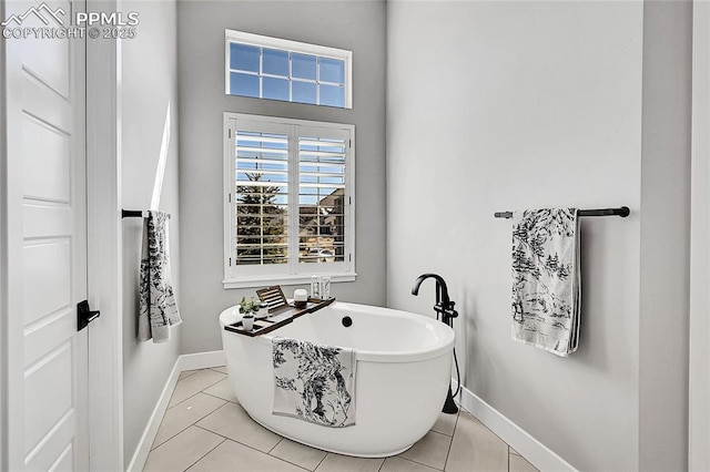 bathroom with tile patterned flooring, baseboards, and a freestanding bath