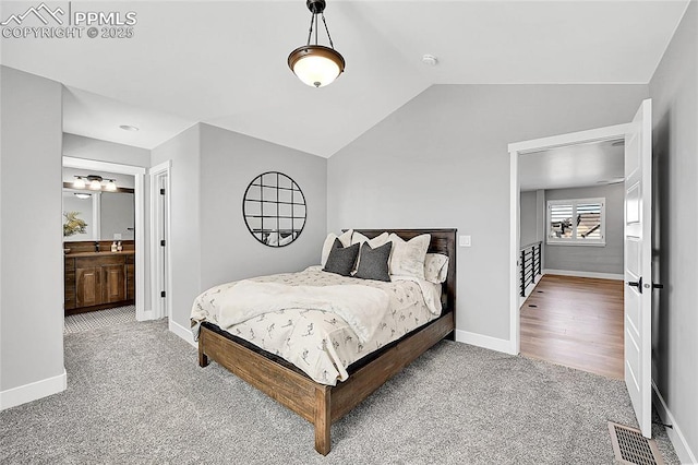 carpeted bedroom with lofted ceiling, ensuite bathroom, visible vents, and baseboards