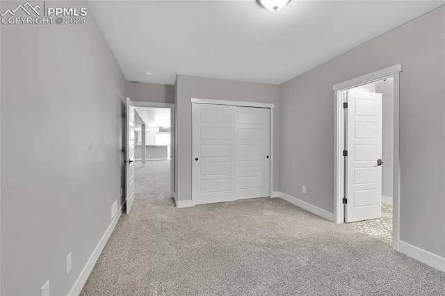 unfurnished bedroom with a closet, baseboards, and carpet flooring