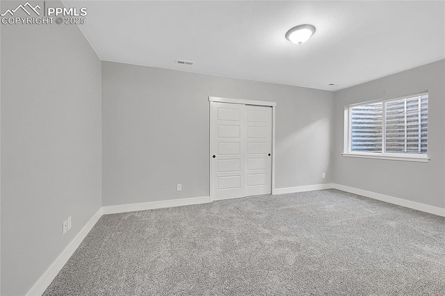 carpeted spare room featuring visible vents and baseboards