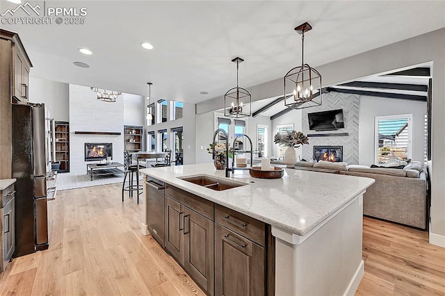 kitchen with a tile fireplace, open floor plan, freestanding refrigerator, and a sink