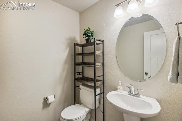 bathroom with a textured wall, a sink, and toilet