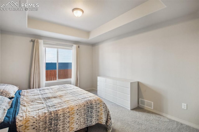 bedroom featuring a tray ceiling, carpet flooring, visible vents, and baseboards