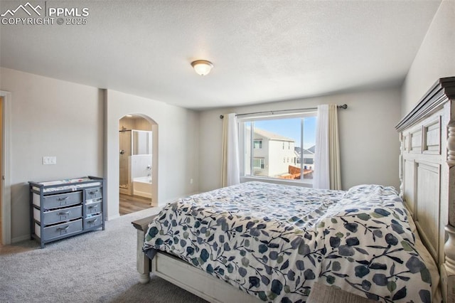 carpeted bedroom with arched walkways and ensuite bathroom