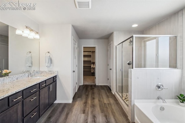 bathroom featuring visible vents, wood finished floors, a spacious closet, vanity, and a shower stall