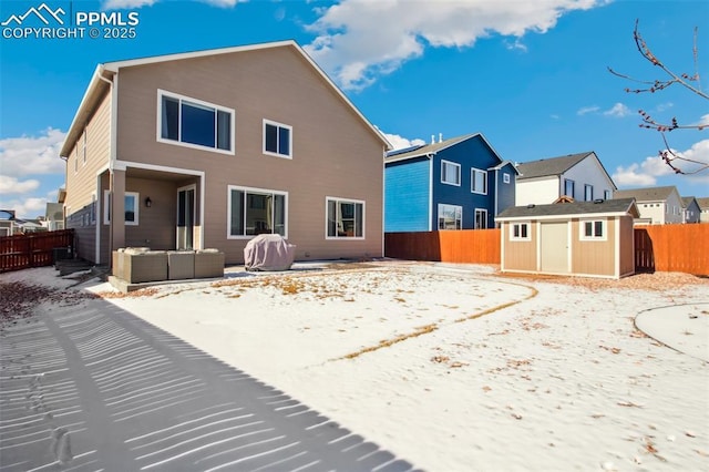 rear view of house with a storage shed, a fenced backyard, a patio, and an outbuilding