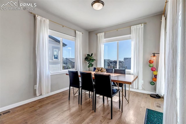 dining room with light wood-type flooring, visible vents, and baseboards