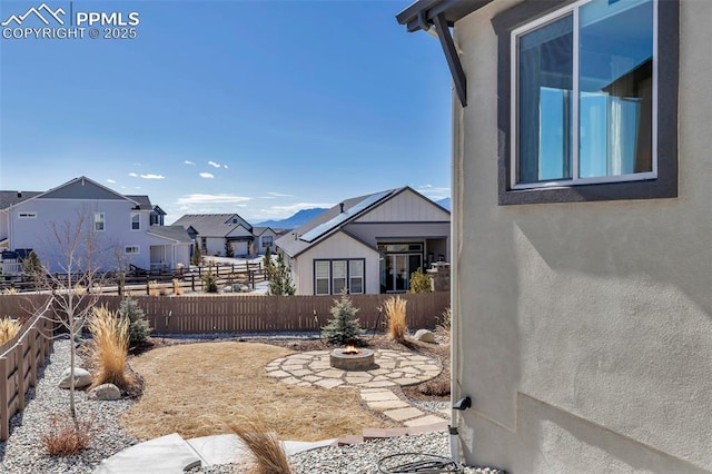 view of yard featuring a fire pit, a fenced backyard, and a residential view