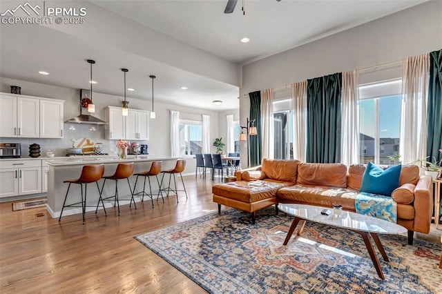 living room featuring ceiling fan, recessed lighting, baseboards, and light wood-style floors