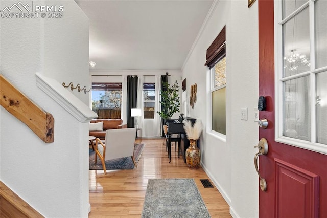 entrance foyer featuring light wood finished floors, visible vents, baseboards, and crown molding