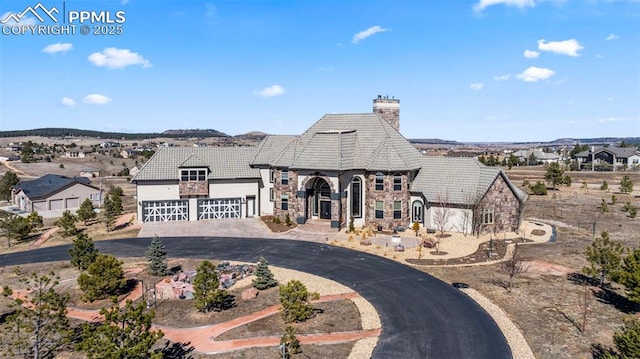 french provincial home featuring aphalt driveway, stone siding, a tile roof, and a chimney