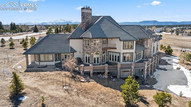 rear view of property featuring a balcony, stone siding, and a mountain view