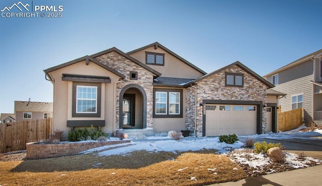 view of front of house featuring a garage, stone siding, fence, and stucco siding