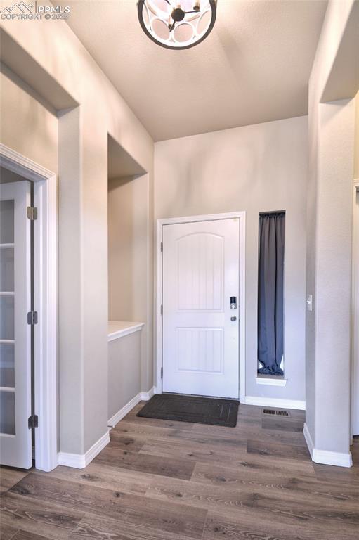 foyer entrance with dark wood-style floors, baseboards, and a chandelier