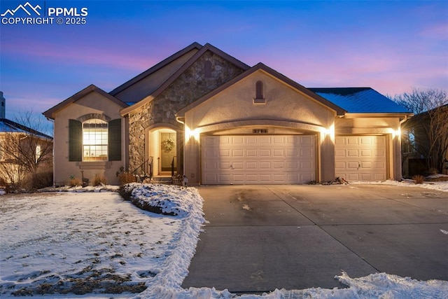 ranch-style house with stone siding, an attached garage, driveway, and stucco siding