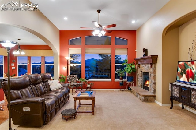 carpeted living area featuring lofted ceiling, recessed lighting, ceiling fan with notable chandelier, a fireplace, and baseboards