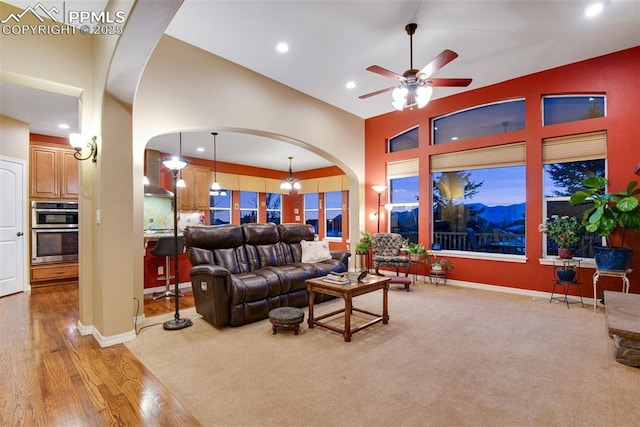 living room featuring recessed lighting, arched walkways, baseboards, and ceiling fan with notable chandelier