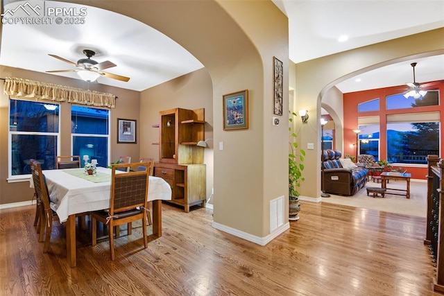 dining area with visible vents, arched walkways, wood finished floors, and a ceiling fan