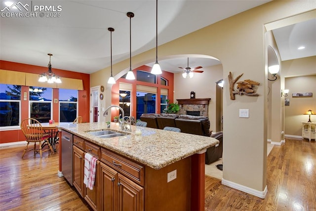 kitchen with a center island with sink, arched walkways, a sink, and decorative light fixtures