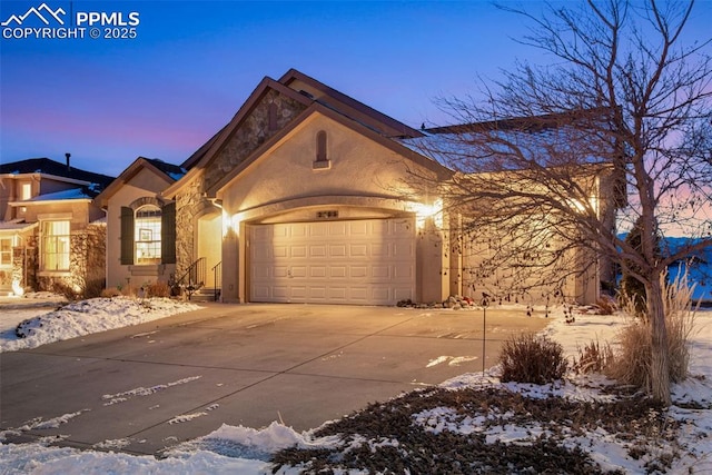 view of front facade with an attached garage, concrete driveway, and stucco siding